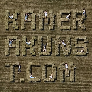 Buchstabenkunst vs. Kamerakunst. Kunstvoll gestapelte Heuballen auf dem Feld, aus der Vogelperspektive mit der Drohne fotografiert, werden als Buchstaben erkennbar.