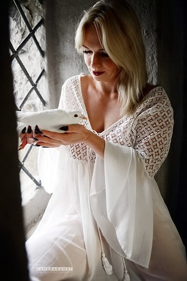 Portrait photography with white dove in style in a medieval castle.