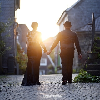 Hand in Hand dem Sonnenuntergang entgegen, das Gothic-Paar im Gegenlicht.