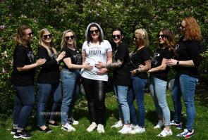 Group photo at bachelorette party, girls hands rest on bride's baby bump